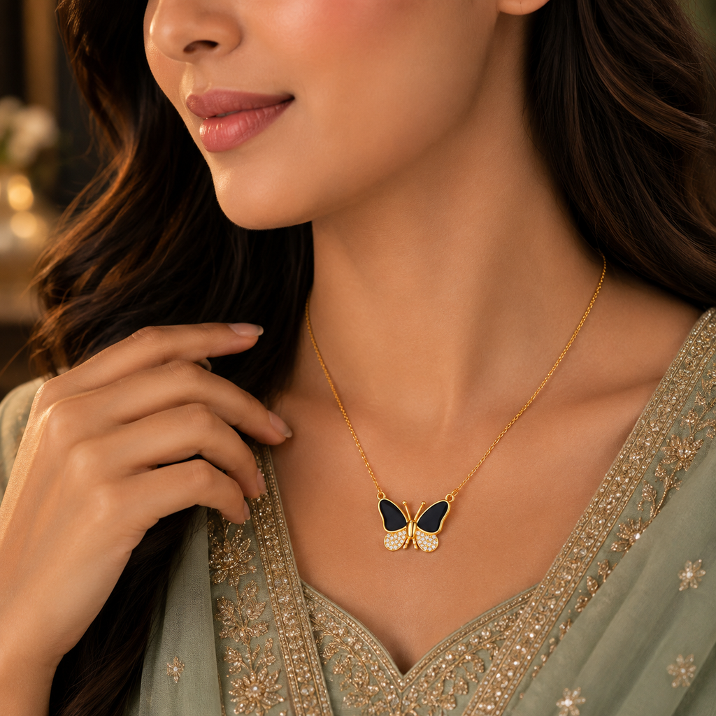Woman wearing black enamel and CZ pave butterfly pendant necklace in gold-tone finish styled with a sage green embroidered Pakistani formal outfit