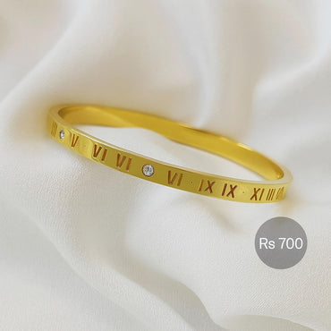 Gold-tone roman numeral bangle with CZ accents on white fabric – Destiny.pk.