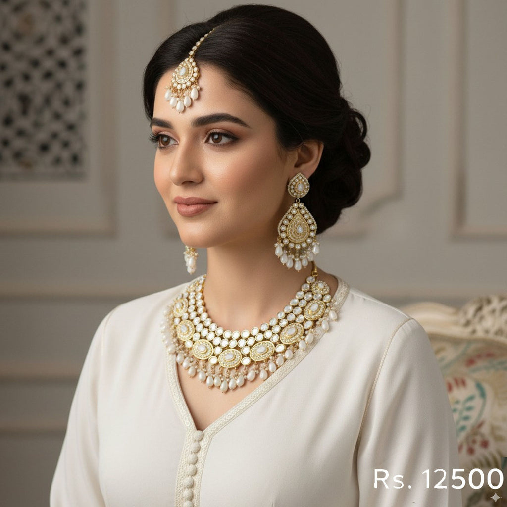 Gold-plated bridal jewelry set with Kundan stones and pearls, including a necklace, jhumka earrings, and tikka, priced at Rs. 12500