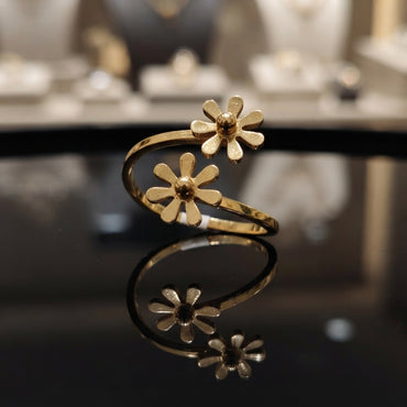 Gold-tone double daisy floral bypass open band ring on reflective surface