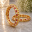 22K Gold-Tone Alternating Ruby & White Square CZ Gold Dome Bead Bridal Bangle Set of 2 on marble surface with crystal glass lantern and white baby's breath flowers backdrop