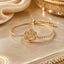 22K Gold-Tone CZ Pavé Rose Flower Charm Tennis Adjustable Bracelet on cream marble surface with ivory satin fabric and gold Mughal decorative tray backdrop