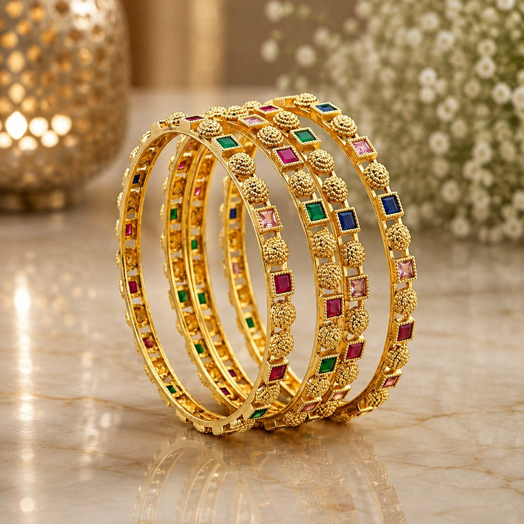 22K Gold-Tone Granule Bead & Multicolor Square CZ Pakistani Bridal Bangle Set of 4 stacked on marble surface with gold moroccan lantern and white baby's breath flowers backdrop