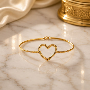 22K Gold-Tone Open Heart Charm Snake Chain Bracelet on cream marble surface with ivory satin fabric and gold Mughal decorative urn backdrop