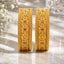 22K Gold-Tone Wide Embossed Floral Repousse & Ruby CZ Bridal Kada Set of 2 standing upright on marble surface with white baby's breath flowers and crystal glass vase backdrop