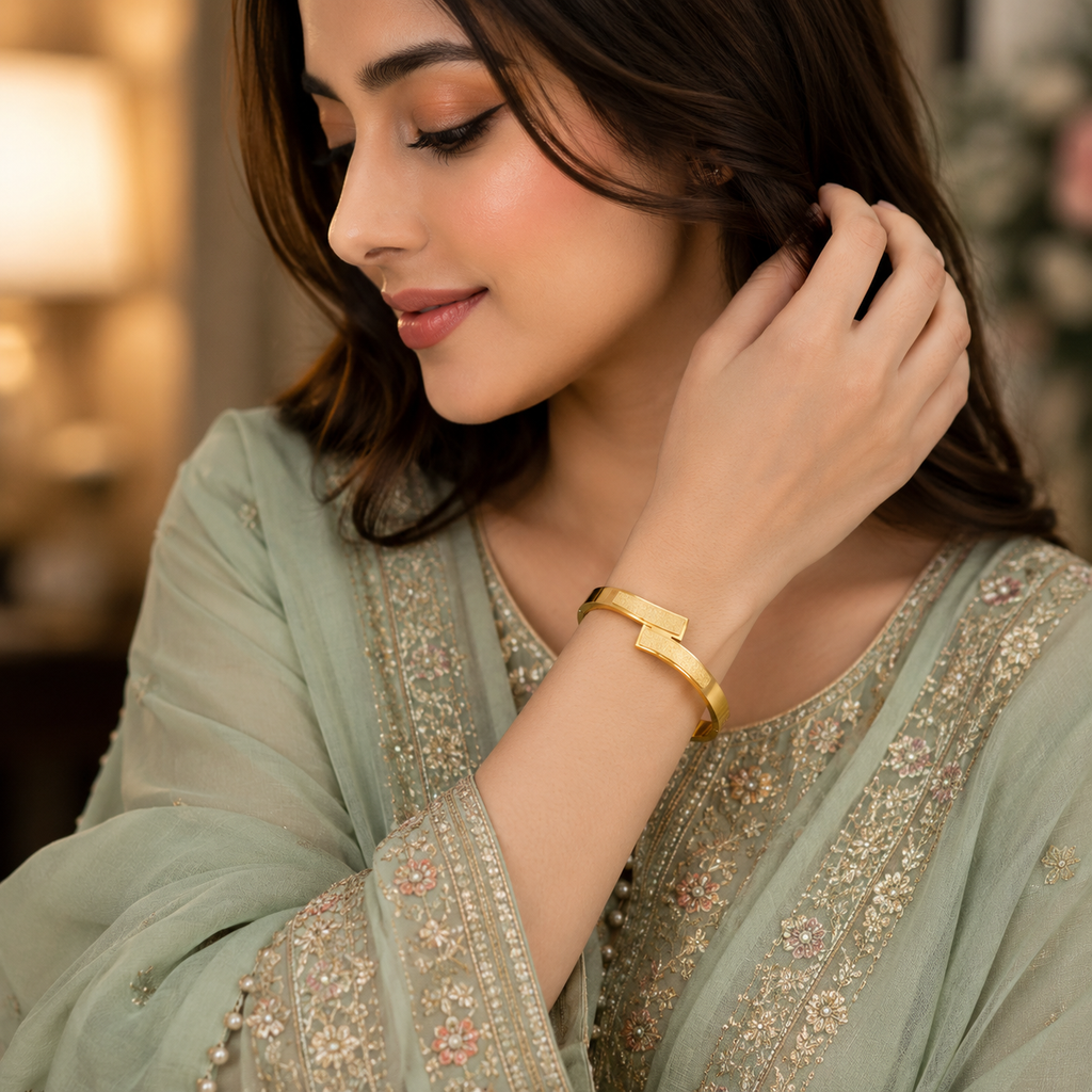 Woman wearing gold-tone dual bar matte and polished open cuff bangle styled with a sage green embroidered Pakistani formal outfit