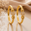 Set of two gold-tone filigree mesh ball triple bead engraved bangle bracelets with floral scroll band and large silver-tone mesh ball centrepiece displayed on cream satin with dried white flowers
