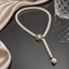 Elegant white pearl Y-drop necklace with floral centerpiece and hanging pearl detail