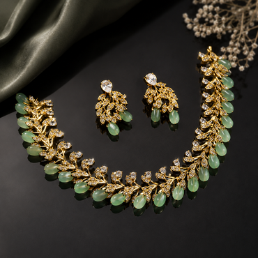 Elegant gold-tone green beaded leaf necklace set with sparkling clear stones and matching earrings