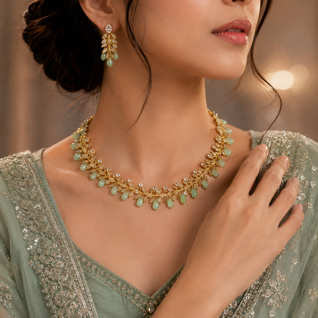 Elegant gold-tone green beaded leaf necklace set with sparkling clear stones and matching earrings