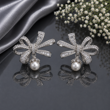 Elegant silver CZ bow pearl drop earrings featuring sparkling clear stones, baguette detailing and luminous pearl drops