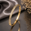 Elegant gold-tone slim bangle with sparkling baguette-cut stone detailing and polished finish