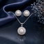 Elegant pearl pendant necklace and matching earrings set with sparkling halo stone detailing