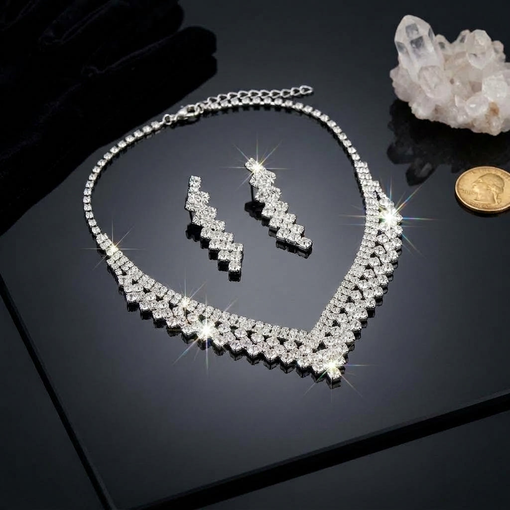 Silver-Tone Pavé White CZ V-Bib Choker Necklace & Zigzag Drop Earrings Bridal Jewelry Set flat lay on black reflective surface with white quartz crystal cluster and gold coin backdrop