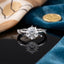 Silver-Tone 6-Prong Round CZ Solitaire & Pavé Shoulder Accent Engagement Ring on black reflective surface with teal blue velvet fabric and gold seal wax stamp backdrop