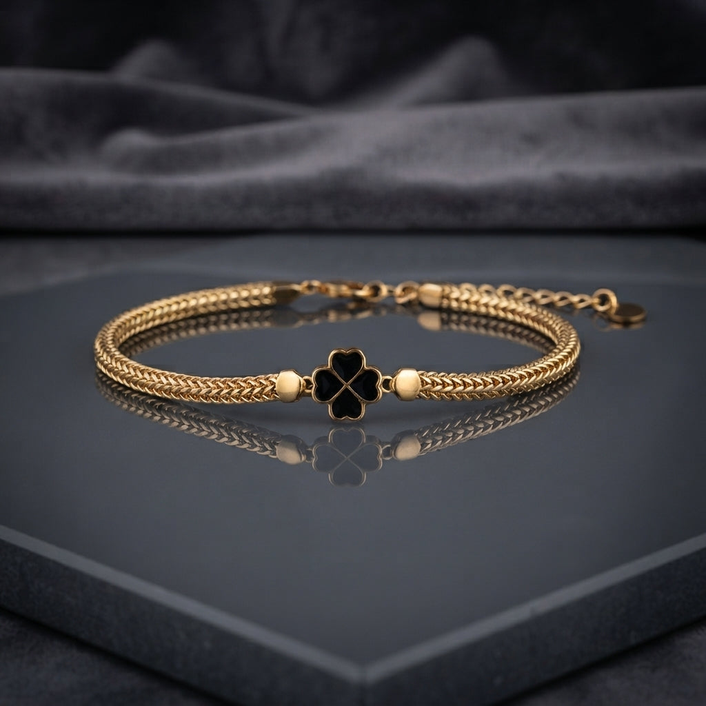 Gold-tone braided bracelet with red four-leaf clover centerpiece
