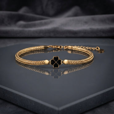 Gold-tone braided bracelet with red four-leaf clover centerpiece