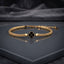 Gold-tone braided bracelet with red four-leaf clover centerpiece