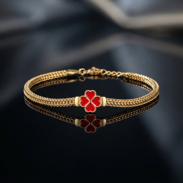 Gold-tone braided bracelet with black four-leaf clover centerpiece