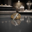 Gold-tone CZ pavé diagonal bar filigree scroll dome ring on reflective grey surface