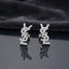 Micro Pavé CZ Monogram Letter Stud Earrings in gold-tone plating flat lay on black mirror surface with grey silk backdrop showing fully encrusted round CZ interlocking letter monogram studs with mirror reflections below