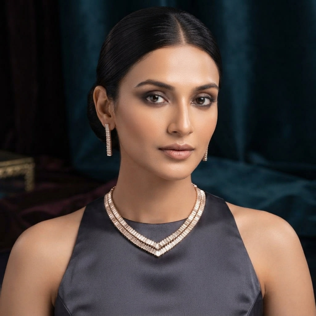 Gold-Tone Double-Row Baguette CZ V-Shape Collar Necklace and Bar Drop Earrings Set worn by model in grey satin halter dress in teal velvet and burgundy backdrop showing double-row baguette CZ V-dip collar necklace and slim vertical baguette CZ bar drop earrings in editorial portrait