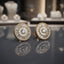 Pair of round silver-tone cubic zirconia stud earrings with a central stone and radiating halo rows.
