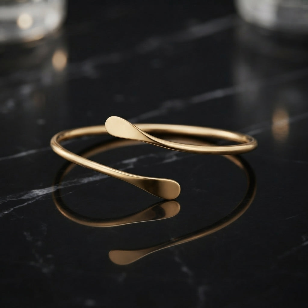 Slim gold-tone open cuff bracelet with a smooth curved band and flattened ends.