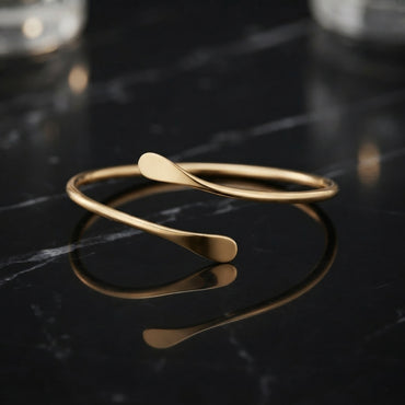 Slim gold-tone open cuff bracelet with a smooth curved band and flattened ends.