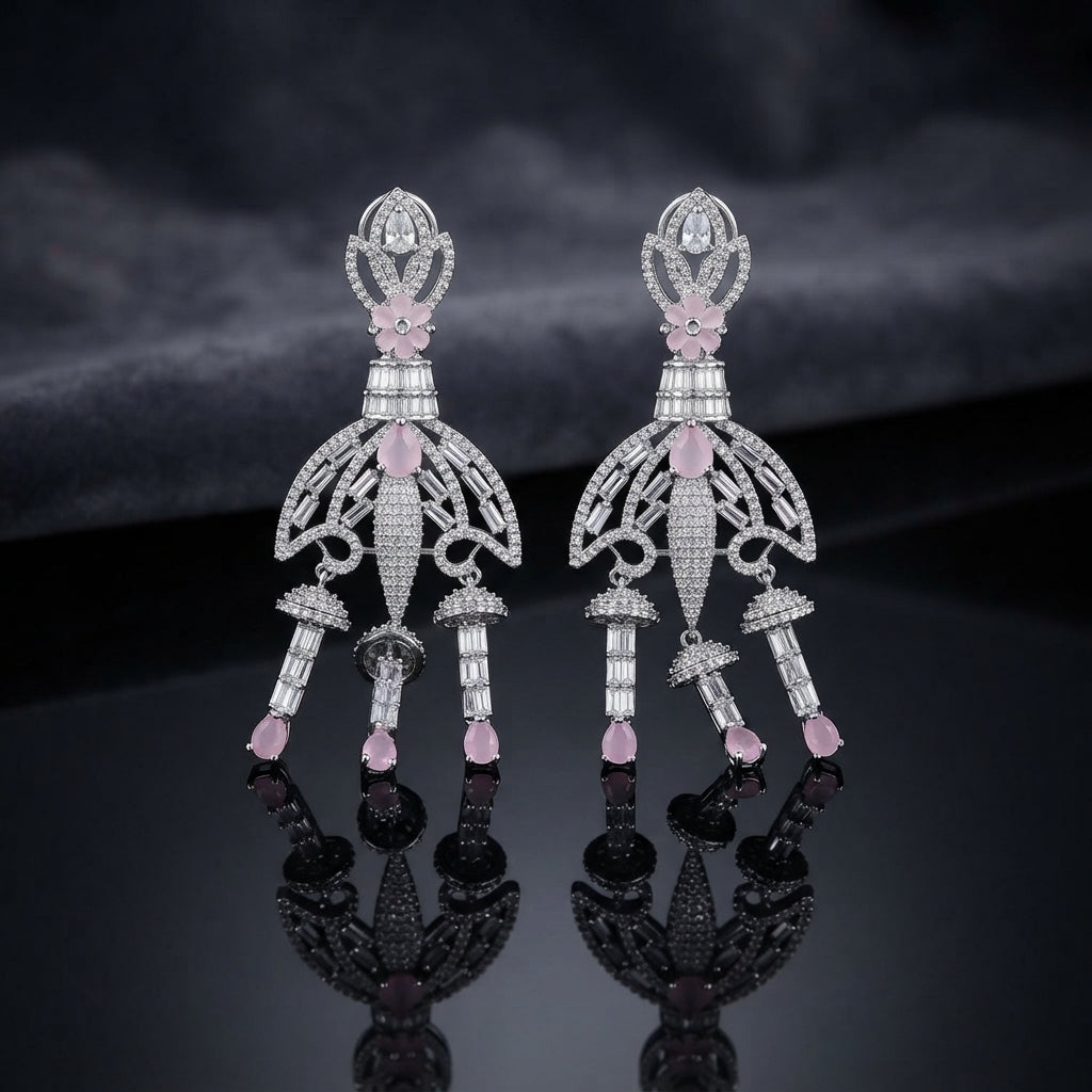 Silver Rose Pink CZ Baguette Crown and Chandelier Fan Jhumka Drop Earrings on dark mirror surface with charcoal fabric backdrop showing rhodium silver grand chandelier jhumka pair with ornate open lotus crown pear white CZ solitaire baguette column open-work fan chandelier body with baguette arch arms 3 tiered jhumka bells and rose pink pear CZ drops