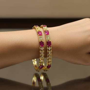 Gold bracelet with red gemstones on a wrist against a neutral background