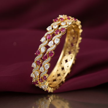 Gold bracelet with red and white stones on a purple fabric background