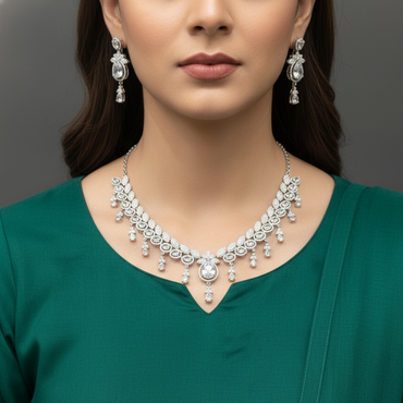 Woman wearing a silver necklace and earrings against a gray background