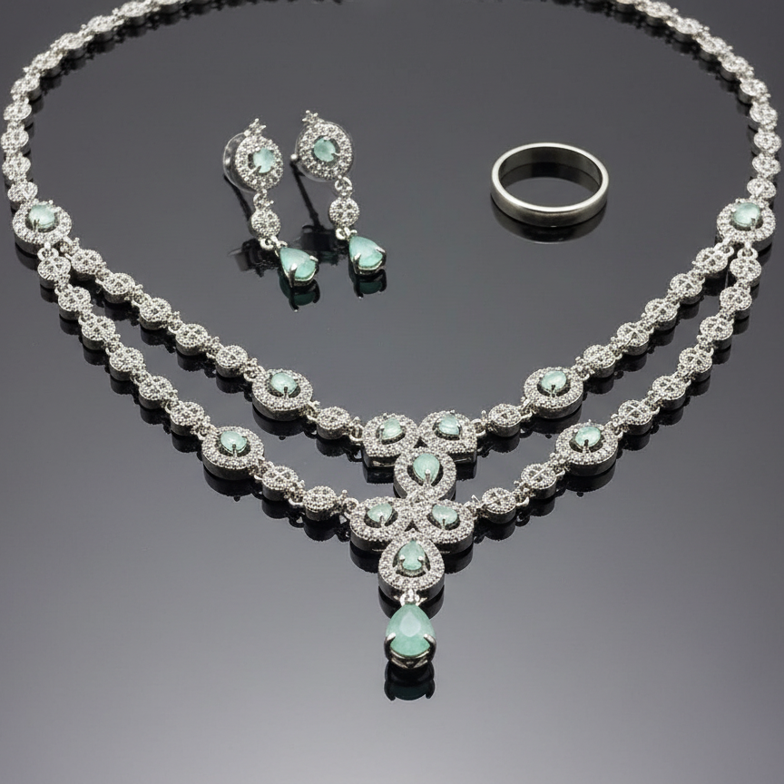 Jewelry set with necklace, earrings, and ring on a reflective surface
