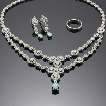 Jewelry set with necklace, earrings, and ring on a reflective surface