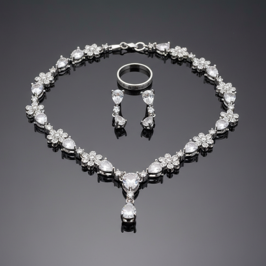 Silver jewelry set with necklace, earrings, and ring on a reflective surface