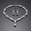 Silver jewelry set with necklace, earrings, and ring on a reflective surface