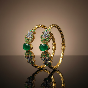 Gold bracelet with green gemstones on a reflective surface