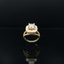 Gold ring with a large central diamond and smaller diamonds on a black background