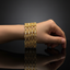 Gold bracelet on a hand against a dark background