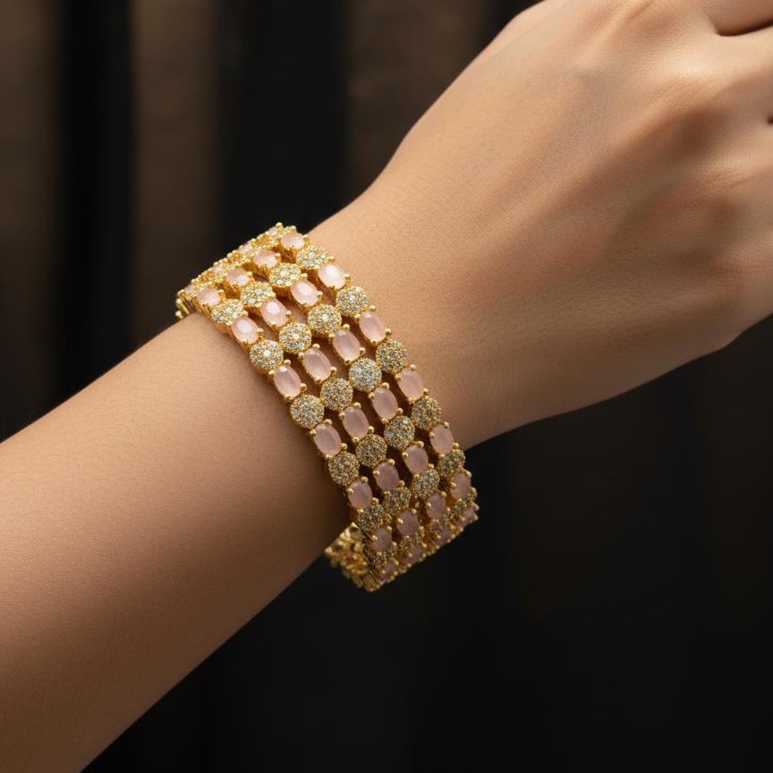 Gold bracelet with pink stones on a wrist against a dark background