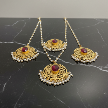 Set of gold and red stone jewelry on a black marble surface