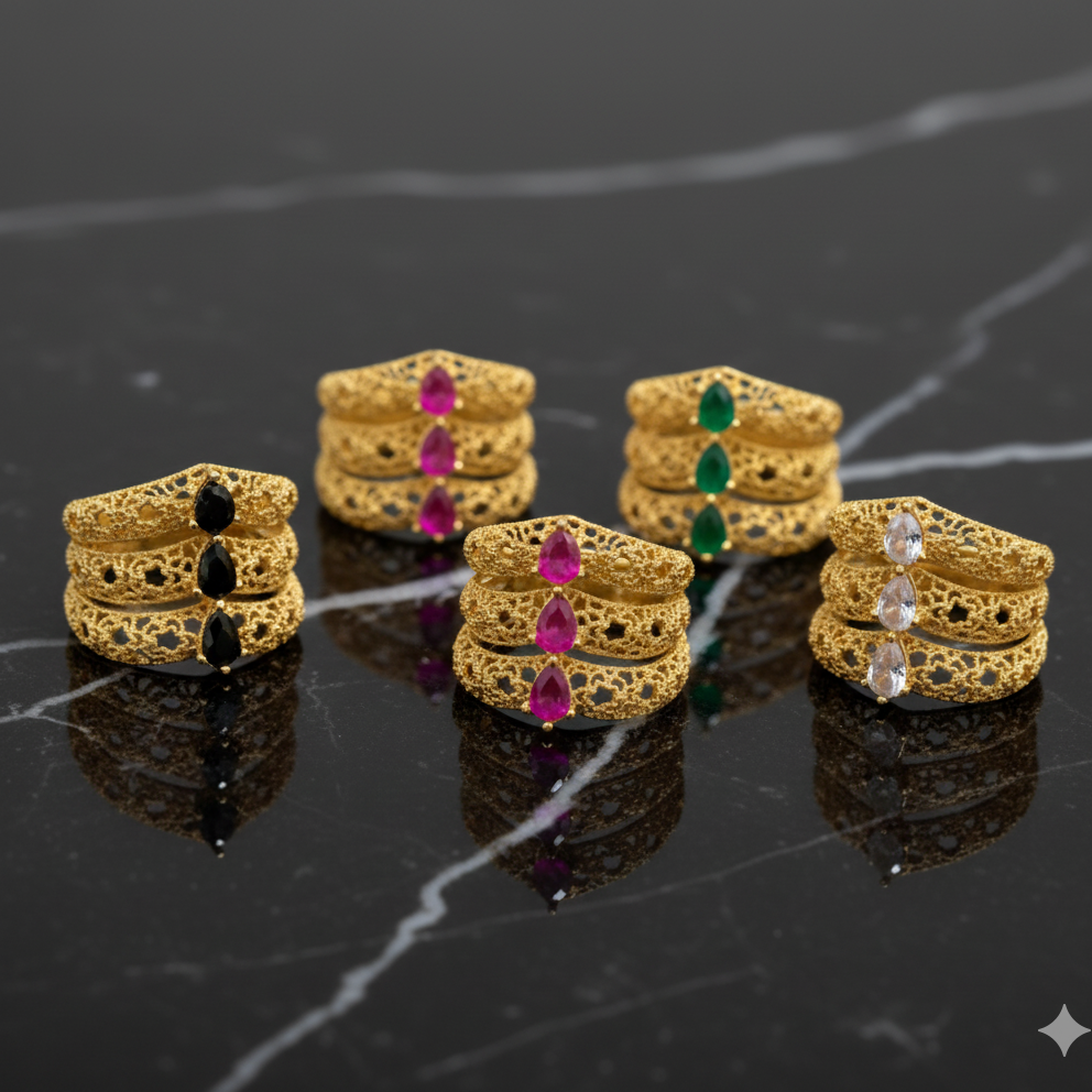 Set of gold rings with gemstones on a dark marble surface