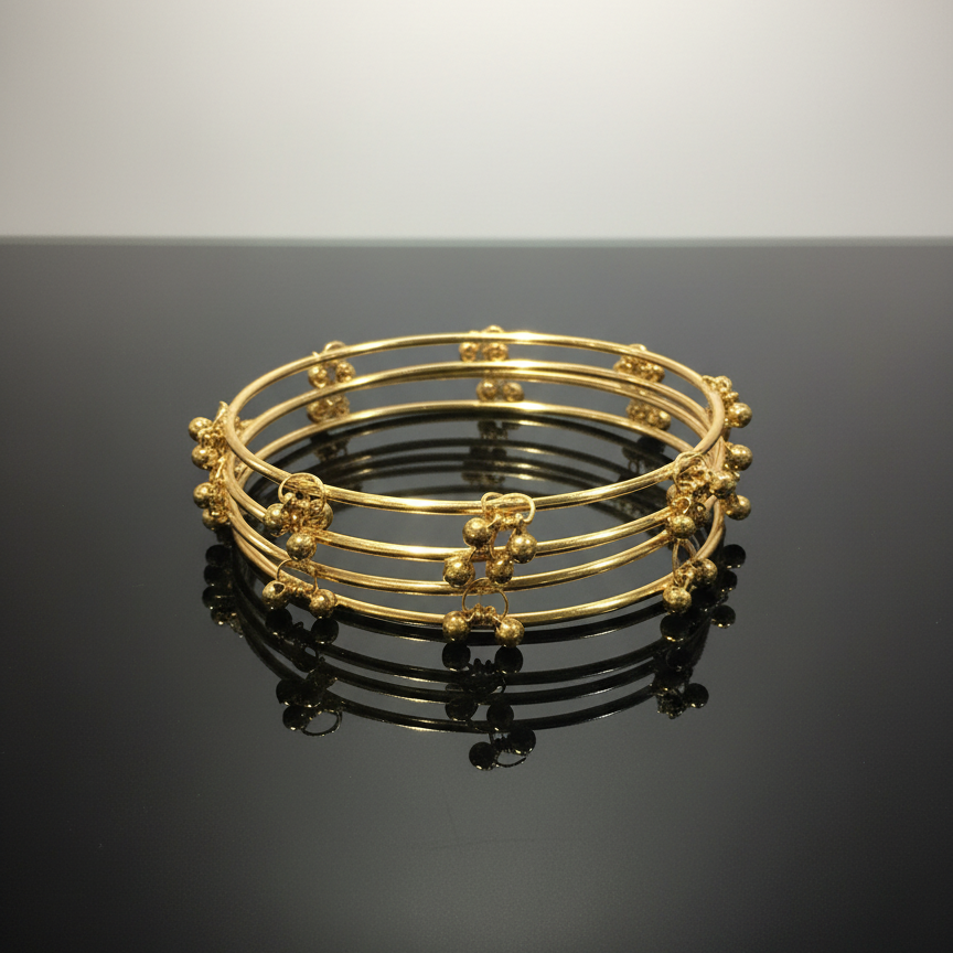 Set of gold bangles on a black surface with a gray background