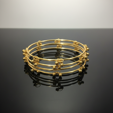 Set of gold bangles on a black surface with a gray background
