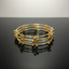 Set of gold bangles on a black surface with a gray background