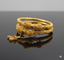 Gold bracelet with intricate design on a reflective surface