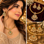 Gold-tone Rajvari necklace and matching earrings with green teardrop accents, clear decorative stones, red earring accents and white pearl-style drops