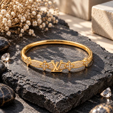 Gold-tone monogram-inspired bangle with sparkling clear crystals, floral motifs and polished gold finish