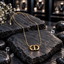 Gold-tone openwork monogram-style pendant with a central vertical detail on a fine chain with an extension chain.